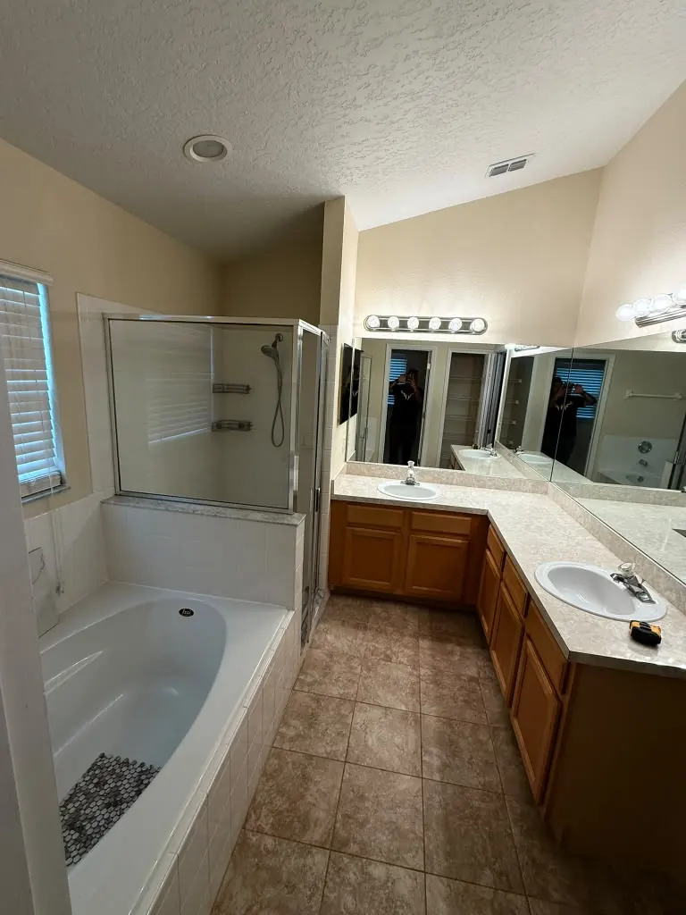 Dated primary bathroom with oak vanity, laminate countertop and a framed shower enclosure before remodeling
